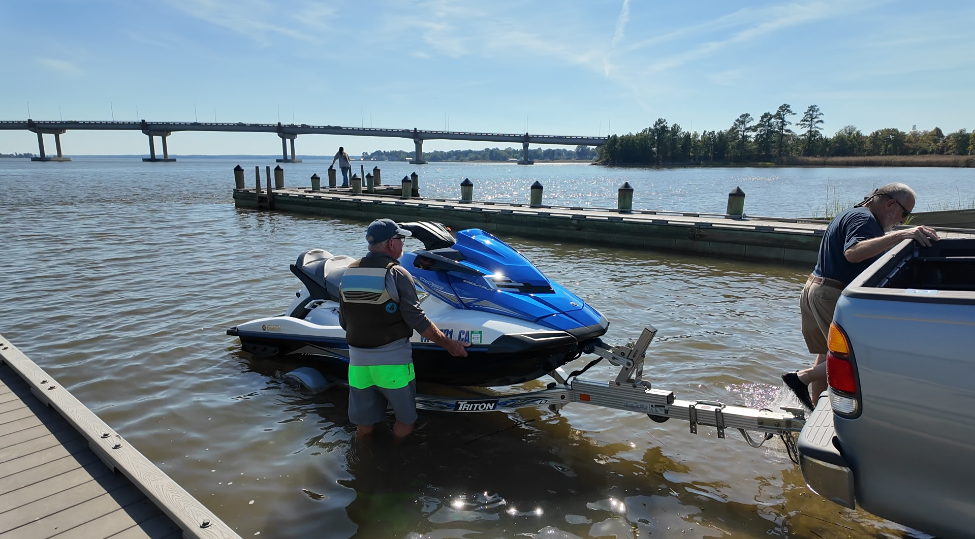 Two people launching a jet ski from a boat ramp
