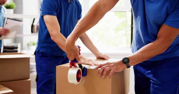 Movers packing up a box